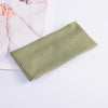 A light olive green knitted headband lying on a white surface next to a piece of pink fabric.