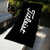 A black microfiber beach towel with white text reading 'Tiltless' is displayed on a white surface.