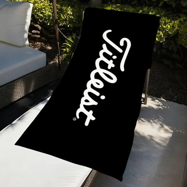 A black microfiber beach towel with white text reading 'Tiltless' is displayed on a white surface.