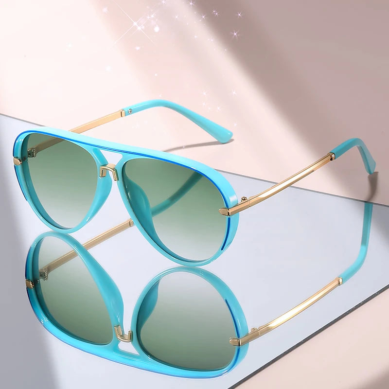 A pair of light blue gradient aviator sunglasses with gold accents resting on a white surface.