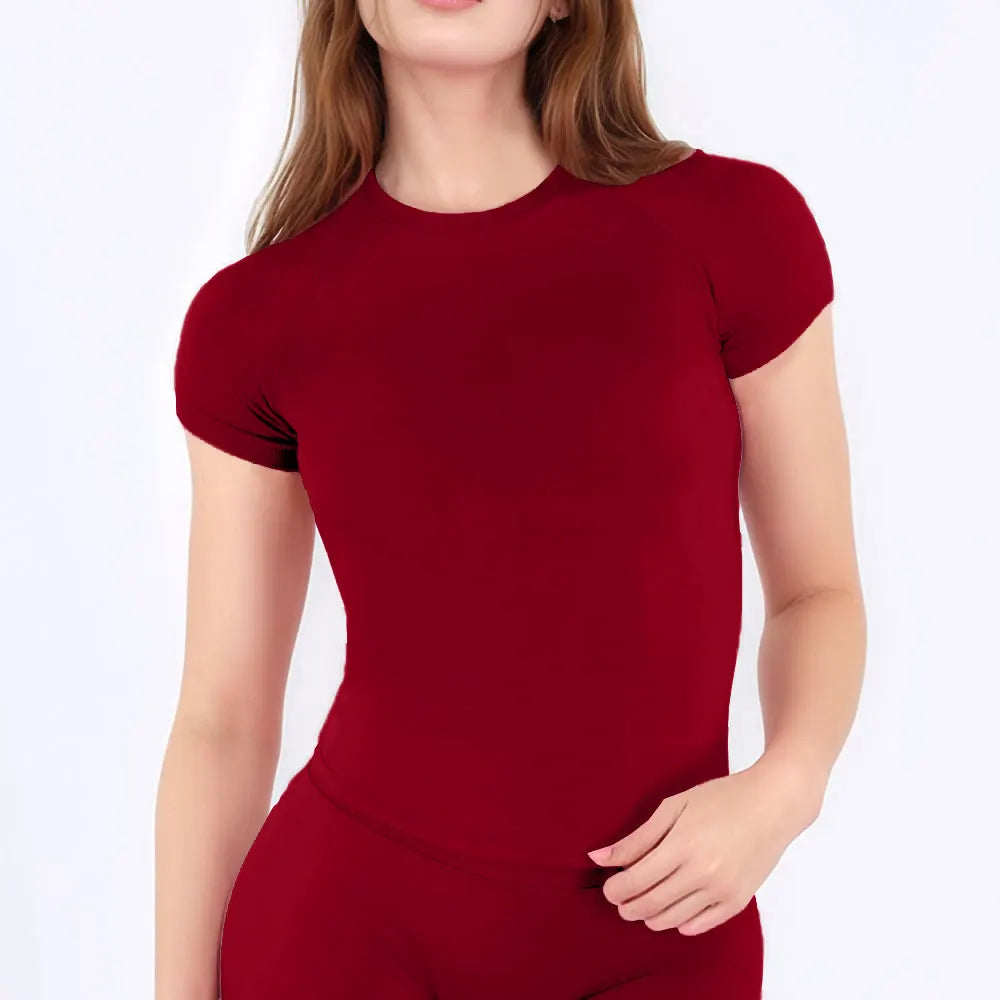 A woman wearing a maroon performance fitness short sleeve top.