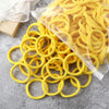A pile of yellow elastic hair bands is shown, some loose and others packaged in a clear plastic bag.