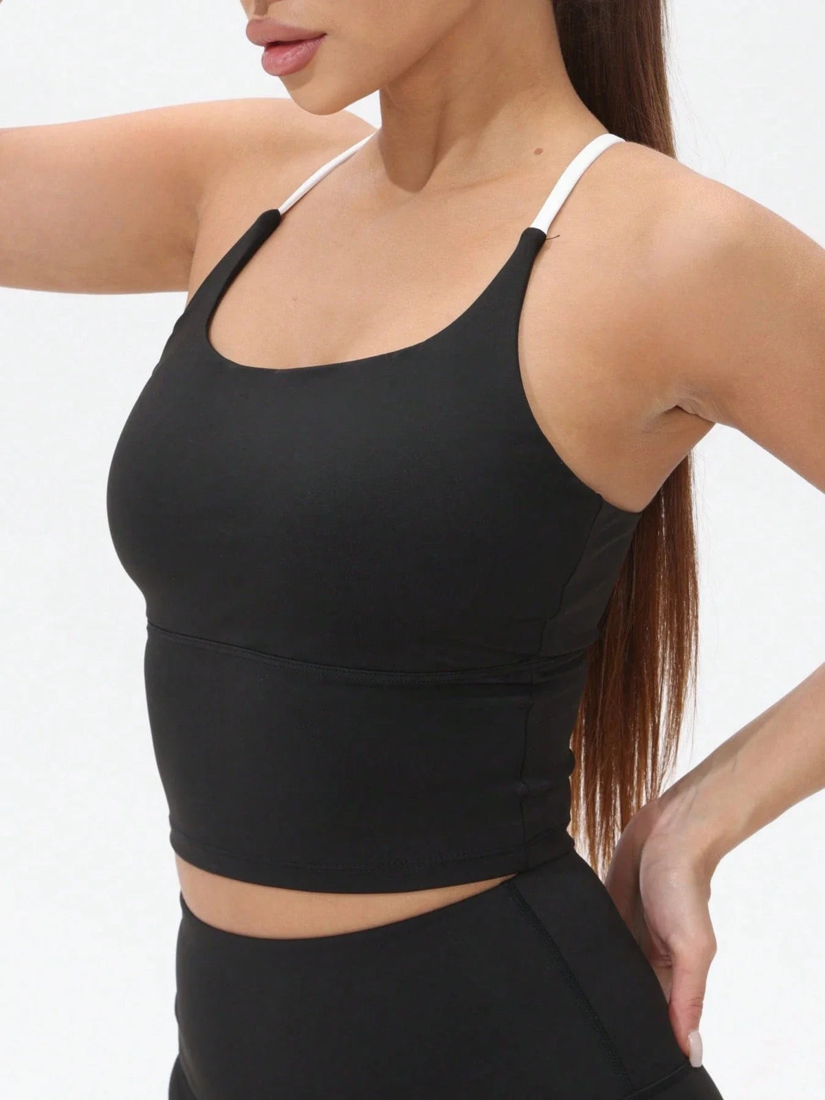 A woman wearing a black women's athletic crisscross tank top with white trim.