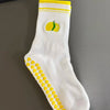 Weiße Strick-Yoga-Socken mit gelben Streifen und einer gelben Zitrusfrucht-Design.
