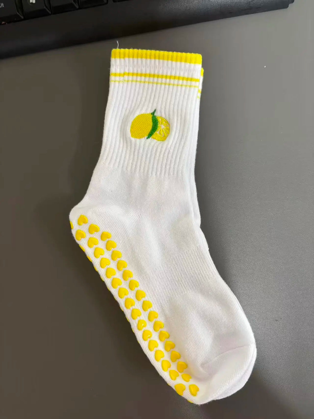 Weiße Strick-Yoga-Socken mit gelben Streifen und einer gelben Zitrusfrucht-Design.