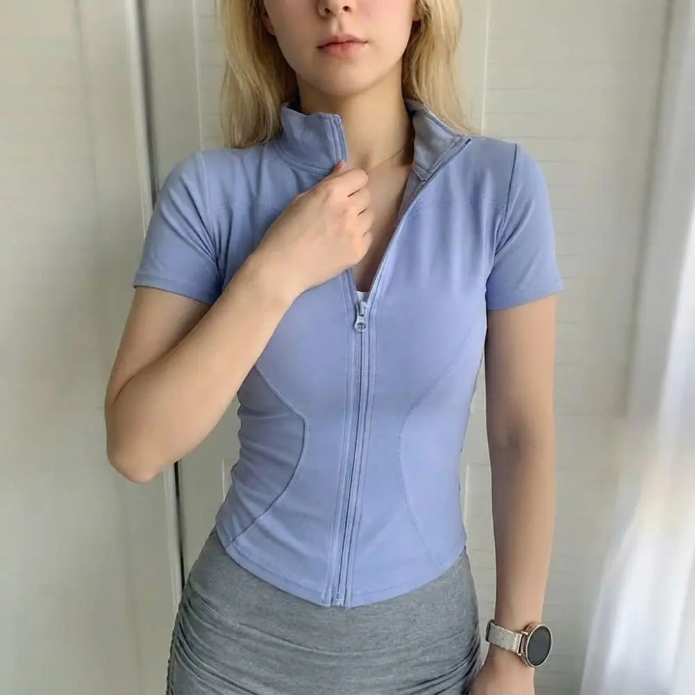 A woman wearing a light blue, long-sleeved sports yoga top and gray skirt.