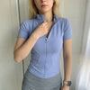 A woman wearing a light blue, long-sleeved sports yoga top and gray skirt.
