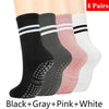 Un juego de cuatro pares de calcetines de yoga y pilates sin deslizamiento para mujer en negro, gris, rosa y blanco.