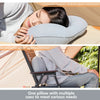 A person rests their head on a light gray inflatable pillow for neck support while relaxing outdoors.