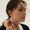 Close-up of a woman wearing magnetic cubic zirconia stud earrings on her ear.