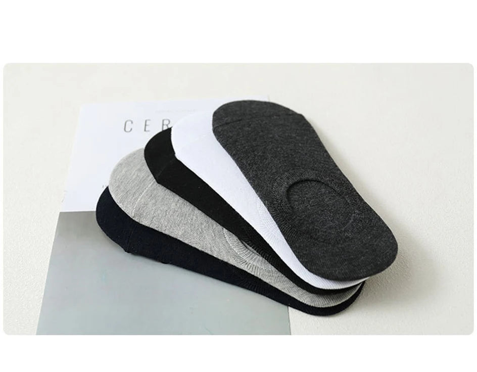 A stack of multi-colored breathable cotton ankle socks in black, gray, and white are displayed on a white surface.