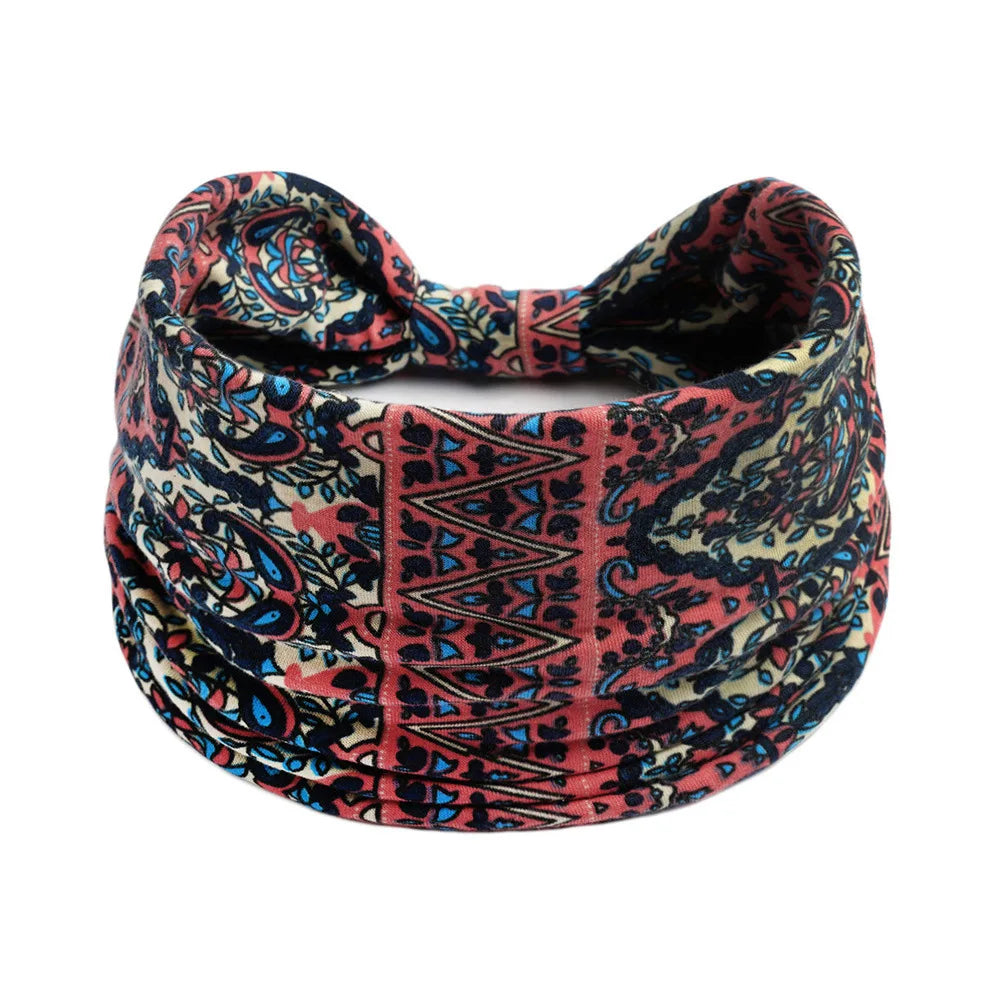 A close-up of a patterned bohemian cotton stretch headband in shades of pink, blue, and black.