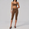 A woman models a brown two-piece yoga and sports tracksuit set consisting of a cropped top and matching leggings.