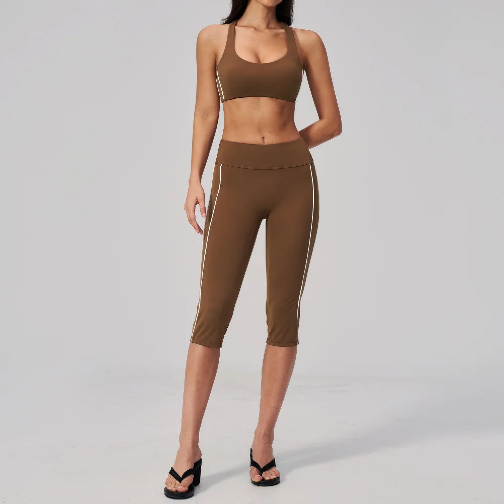 A woman models a brown two-piece yoga and sports tracksuit set consisting of a cropped top and matching leggings.