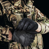 A close-up of a person wearing black tactical touch screen gloves while in camouflage military attire.