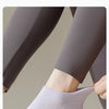 Gros plan de chaussettes de yoga grises portées sur un pied et une jambe.