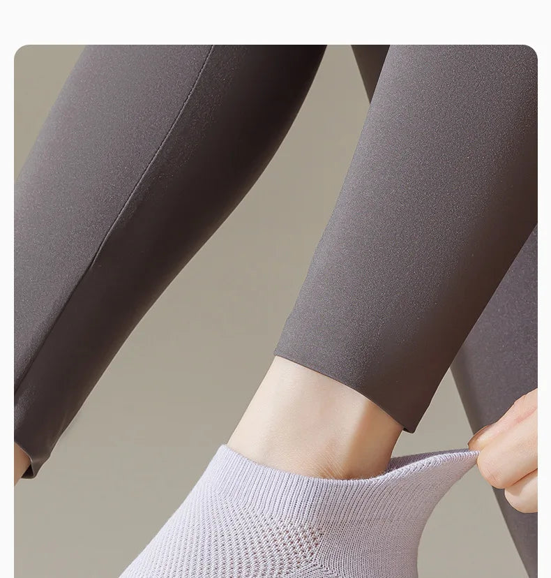 Gros plan de chaussettes de yoga grises portées sur un pied et une jambe.