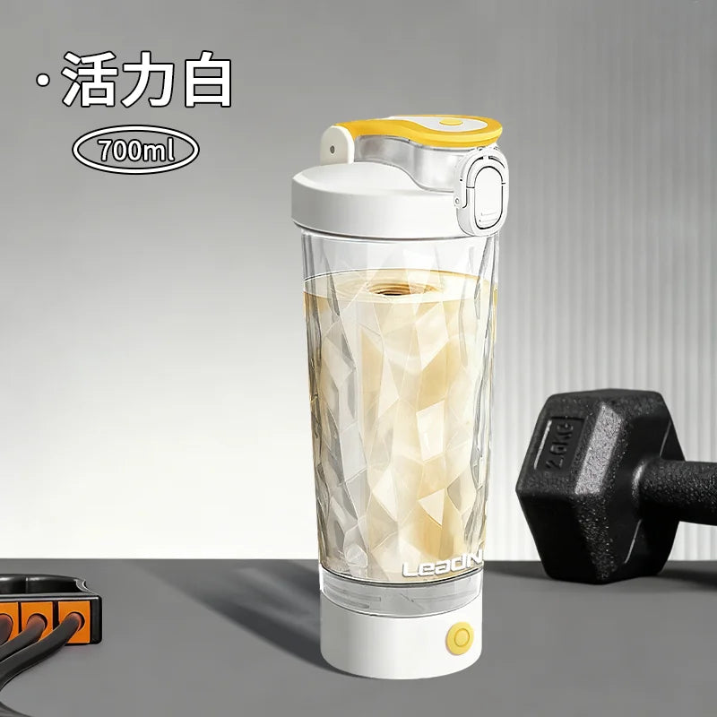 A clear, portable electric shaker bottle with a yellow cap and white base is shown filled with a light-colored liquid.