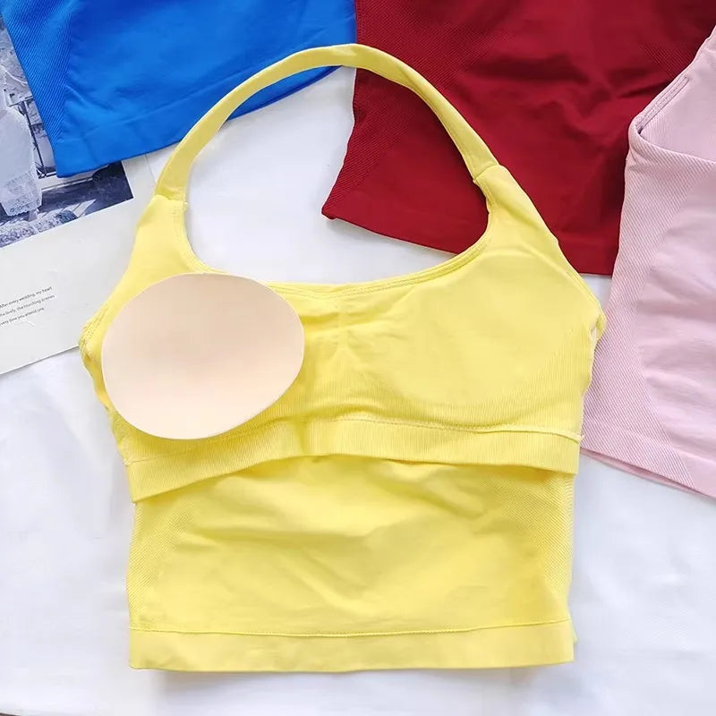 A yellow seamless sports camisole top is displayed next to a red and pink athletic shirt.