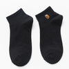 A pair of black cotton socks with an embroidered owl design on the toe.
