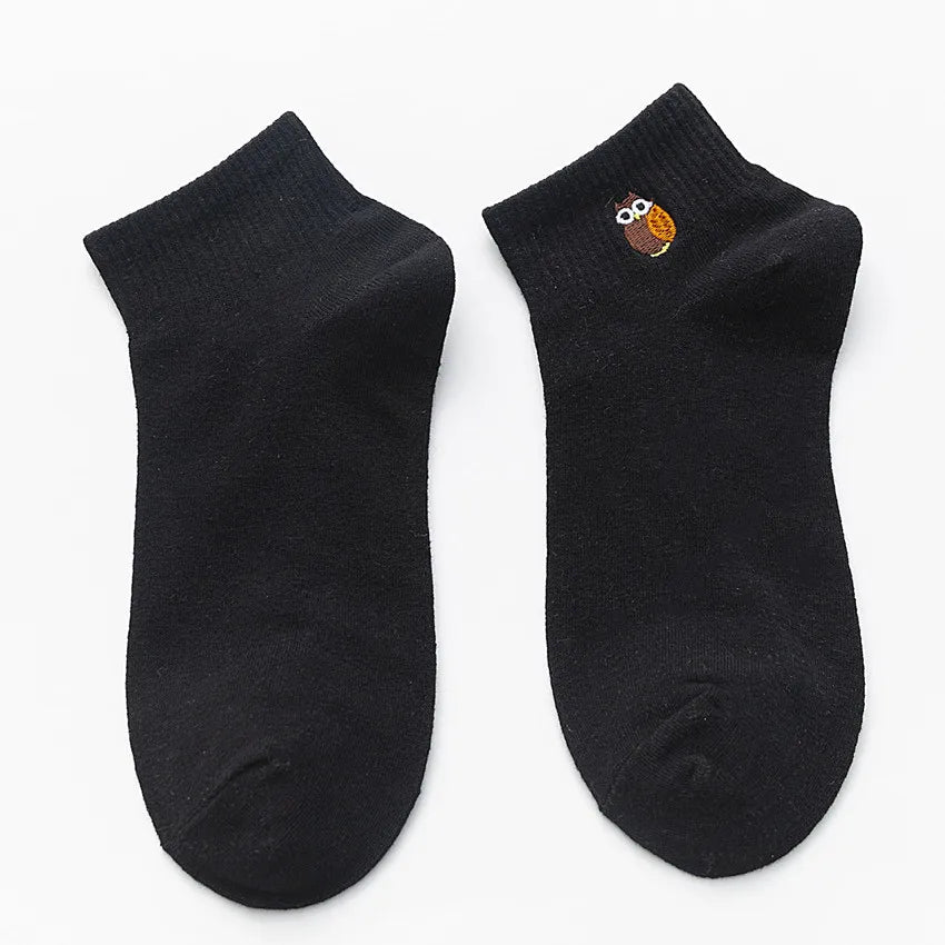 A pair of black cotton socks with an embroidered owl design on the toe.