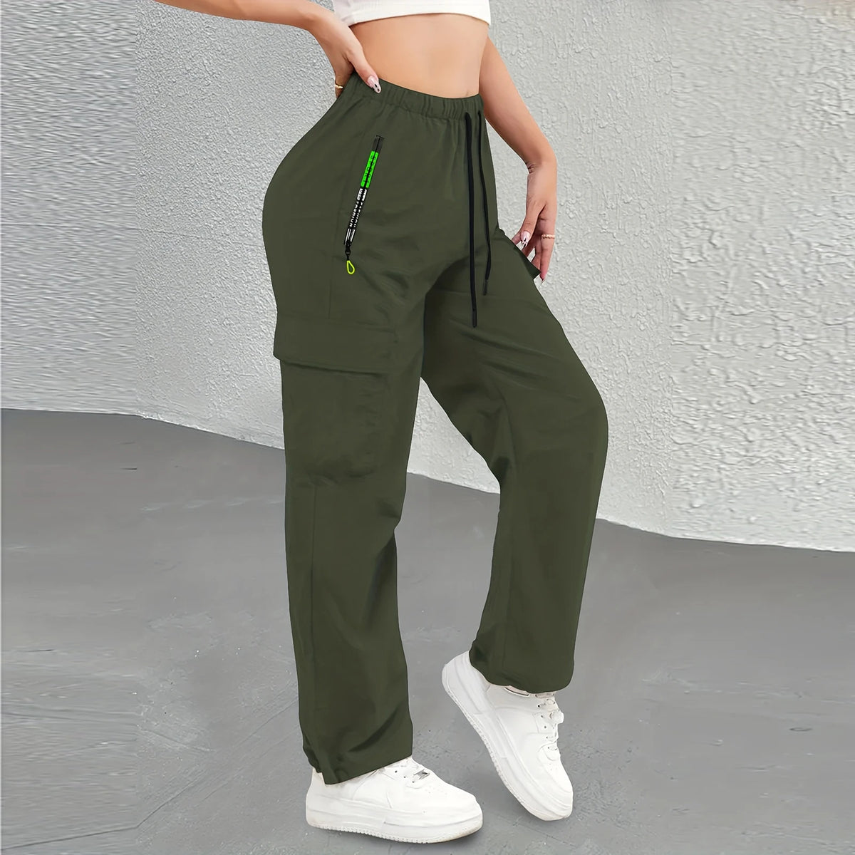 A woman wearing olive green drawstring cargo pants with a black zipper detail.