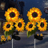 Three solar sunflower LED stake lights with yellow petals and dark centers are displayed against a snowy night background.