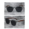 A pair of dark gray sunglasses with brown wood grain frames and lenses set against a gray textured background.