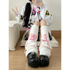 A person wearing white Gothic Lolita heart bow leg warmers and black boots.