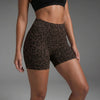 Un modèle portant des shorts de yoga taille haute à imprimé léopard marron et un soutien-gorge de sport noir.