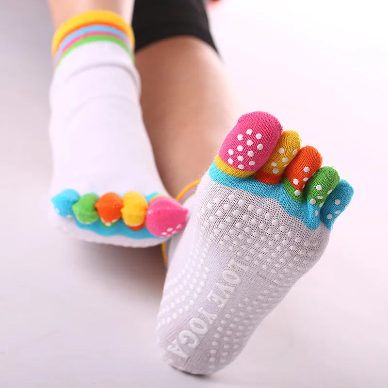 Rainbow yoga socks with colorful toe grips worn on a foot.