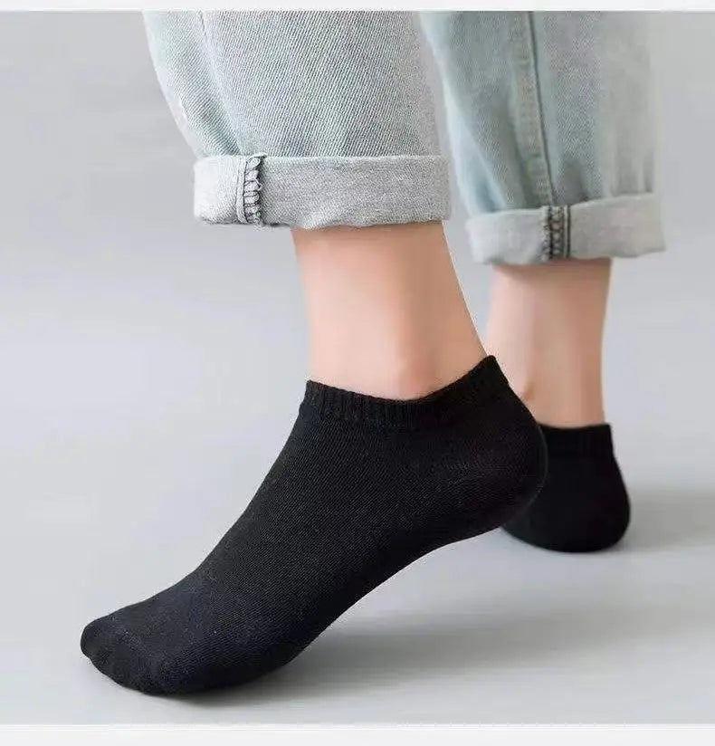 Un par de calcetines de barco negros y casuales y transpirables puestos en el pie de una persona, visibles contra pantalones 