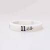 A white silicone wristband with the number 11 and a small signature etched on it.