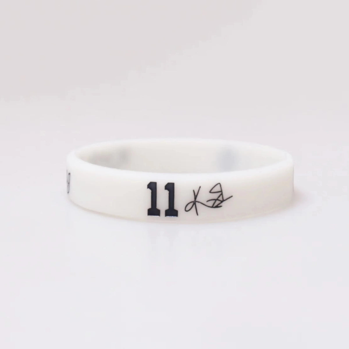 A white silicone wristband with the number 11 and a small signature etched on it.
