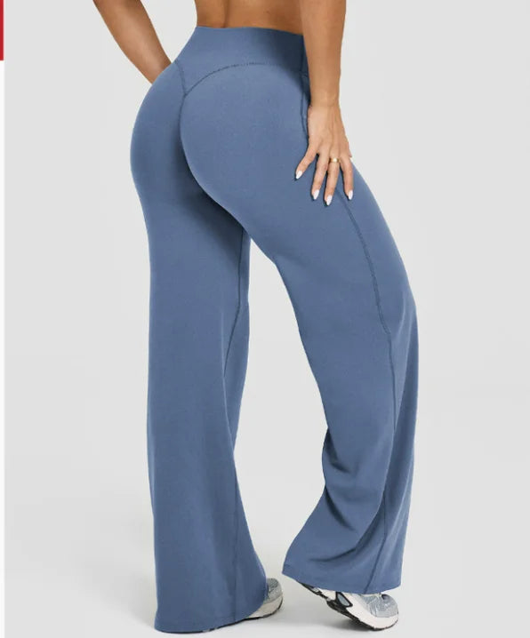 A model is wearing high waisted blue yoga pants while standing.