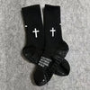 A pair of black athletic socks with white crosses printed on the toes.