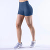 A person wearing navy blue seamless high-waisted yoga shorts and white athletic shoes.