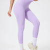 Model in seamless purple yoga leggings and matching crop top, looking down.