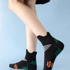 Black massage and compression running socks with green and white patterns worn on a person's foot.