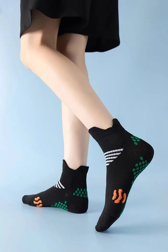 Black massage and compression running socks with green and white patterns worn on a person's foot.