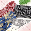 Una colección de diademas de tela estampada en rojo, negro y azul exhibidas sobre un fondo claro.