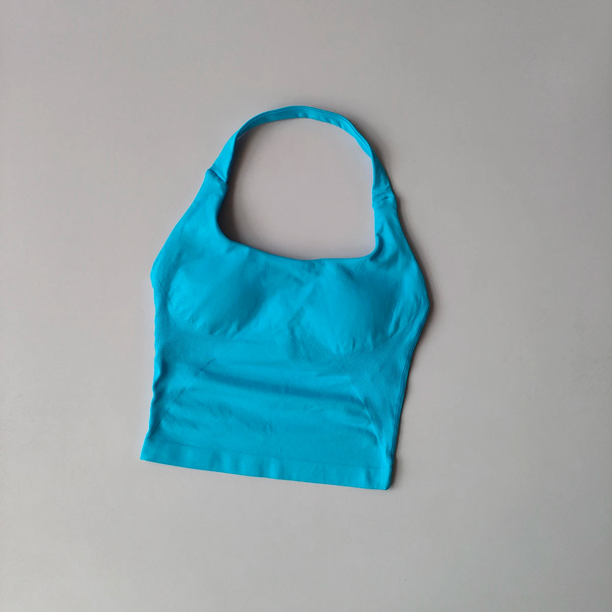 Haut sans coutures cyan pour femmes, style halter, pour yoga et fitness, sur fond gris clair.