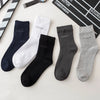 A flat lay of five pairs of men's bamboo fiber socks in black, white, gray, and charcoal colors.