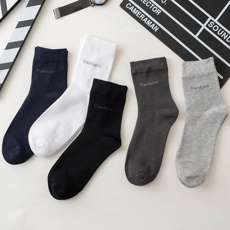 A flat lay of five pairs of men's bamboo fiber socks in black, white, gray, and charcoal colors.