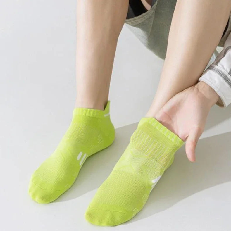 A pair of neon yellow breathable running socks being held by a hand.