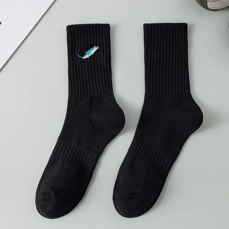 A pair of black men's athletic crew socks with a light blue embroidered design on the foot.