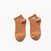 A pair of brown knitted cotton socks with a white embroidered animal on the toe.