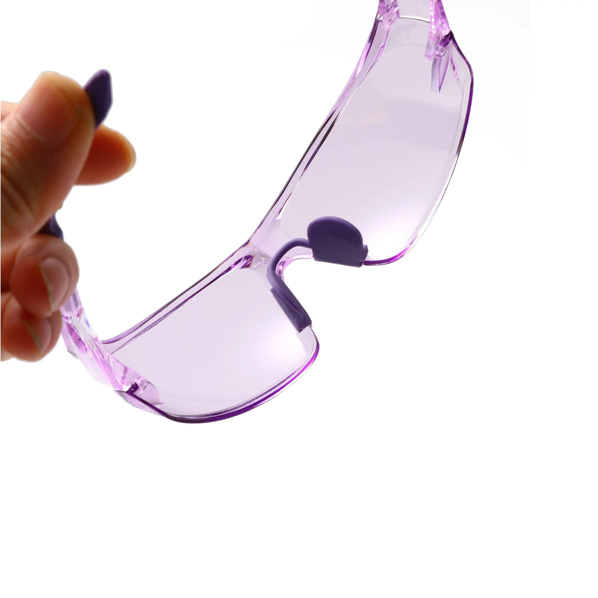 A hand holds a pair of clear purple safety goggles for outdoor and work use.