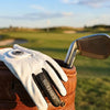 Gant de golf en cuir marron Covevos posé sur un club de golf.