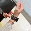 A hand is holding a black leopard print silicone watch band on a wrist, next to a box.